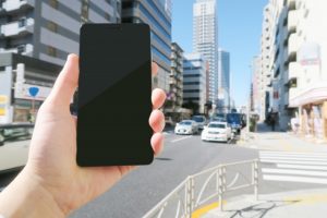 街中でスマホを使ってビーコンを探すイメージ